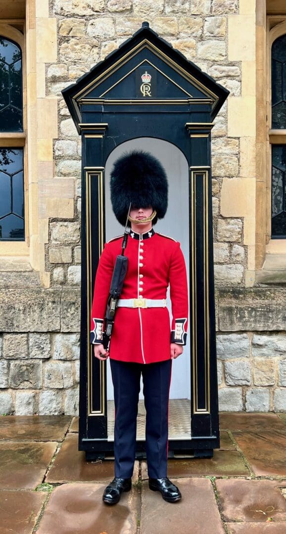 Here's an alt tag for the image: Guardsman in red uniform at Buckingham Palace.