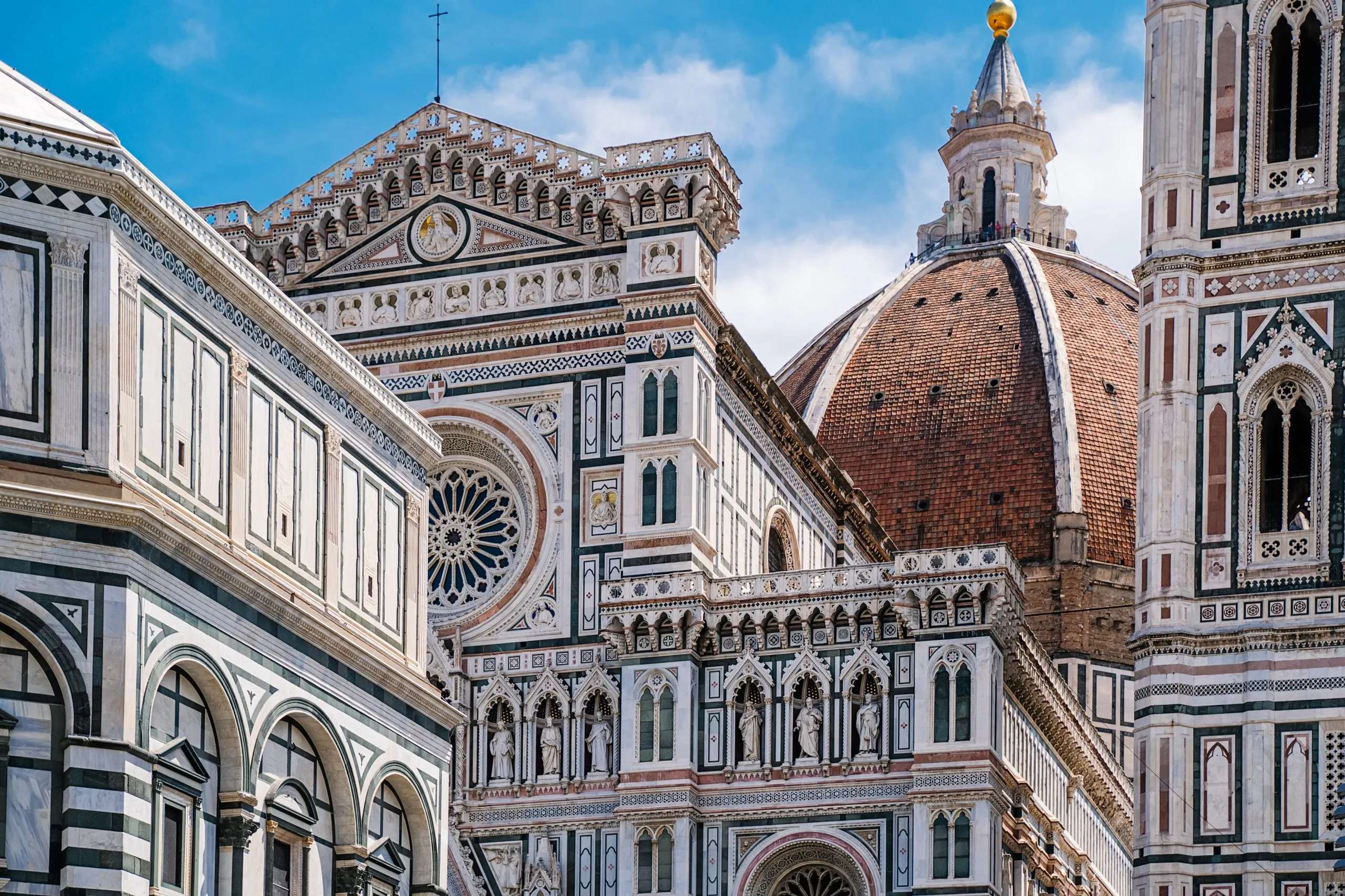 A building with a clock and a dome in the background.