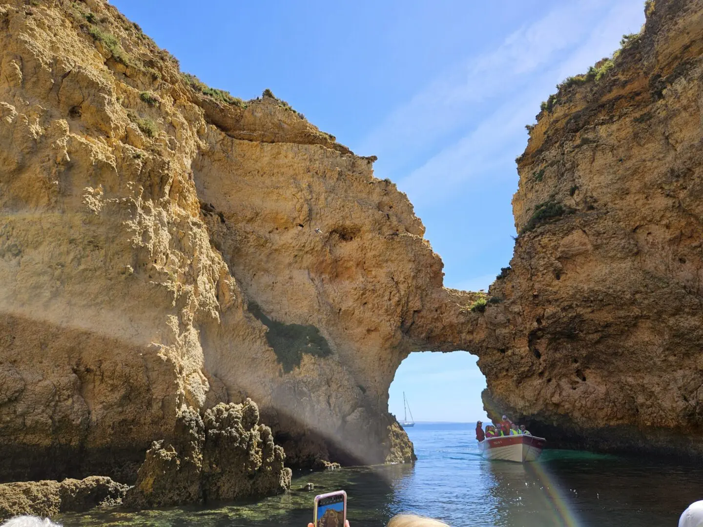 Boat sailing through a natural rock arch.