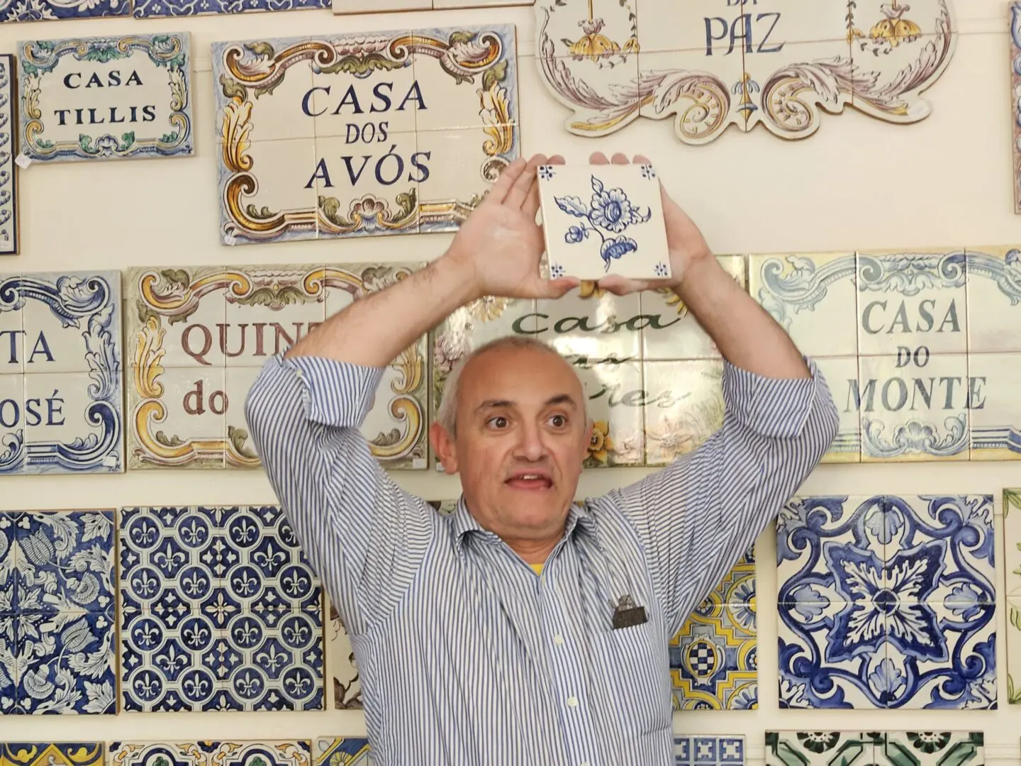 Man holding a Portuguese tile in front of wall.