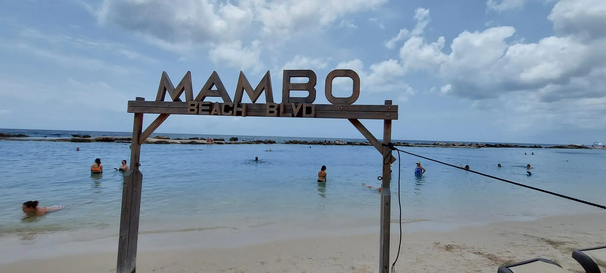 Mambo Beach Blvd sign with people swimming.